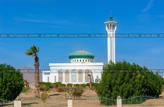 Sharm El Sheikh, Egypt - November 13, 2024: Minaret in traditional oriental style against the blue sky and landscape of the Al Salam Mosque. Редакционное фото, фотограф Григорий Стоякин / Фотобанк Лори