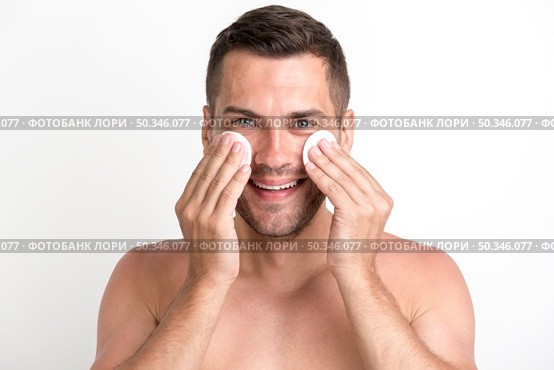 shirtless man cleaning his face with batting cotton pads white background looking camera. Стоковое фото, агентство Ingram Publishing / Фотобанк Лори