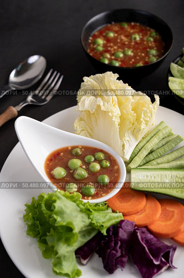 Shrimp-paste sauce in a bowl on the white plate with cucumber, yard long bean, thai eggplant, fried white cabbage, carrots and salad. Стоковое фото, агентство Ingram Publishing / Фотобанк Лори