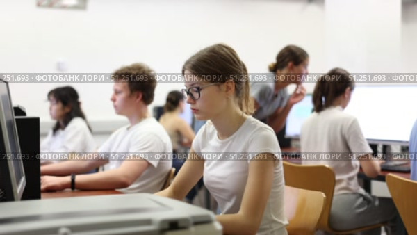 Side view on focused teenager female student sitting at desk in computer class, preparing for exam. Стоковое видео, видеограф Яков Филимонов / Фотобанк Лори
