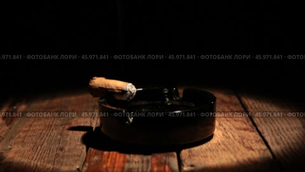 Сигара лежит в пепельнице на деревянном столе. Освещенная прожектором. Панорама. Стоковое видео, видеограф Александр Собко / Фотобанк Лори