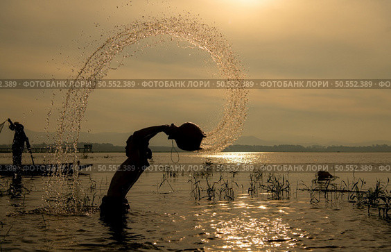 Silhouette of a fisherman in the water at sunset, Thailand. Стоковое фото, агентство Ingram Publishing / Фотобанк Лори