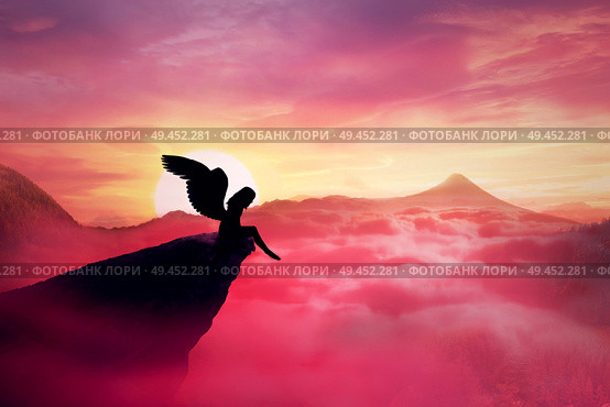 Silhouette of a lonely fallen angel with long wings standing on a cliff against a paradise sunset. Dusk sky over the clouds in the mountains. Heaven landscape scene screen saver. Стоковое фото, агентство Ingram Publishing / Фотобанк Лори