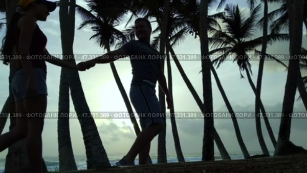Silhouettes of lovers on the background of palm trees and sunset. Стоковое видео, видеограф Mikhail Davidovich / Фотобанк Лори