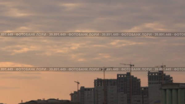 Силуэты строительных кранов вращающихся над строящимися высотными зданиями на фоне вечернего неба. Стоковое видео, видеограф Цыбин Вадим / Фотобанк Лори