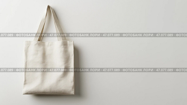 Simple cream-colored tote bag hanging against a light gray wall, copy space. Простая сумка-тоут кремового цвета на фоне светло-серой стены, копия. Стоковое AI-изображение, AI-художник Katsiaryna Repich / Фотобанк Лори