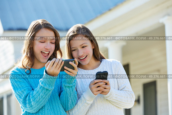 Sister twins having fun with technology mobile smartphone. Стоковое фото, агентство Ingram Publishing / Фотобанк Лори
