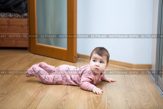 Six month baby trying to creep on laminate floor in domestic room. Стоковое фото, фотограф Кекяляйнен Андрей / Фотобанк Лори