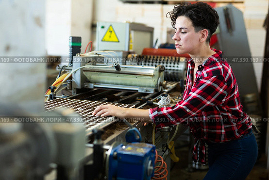Skilled farmer woman working with automatic filling and seeding line for growing containerized seedlings of decorative plants in greenhouse. Стоковое фото, фотограф Яков Филимонов / Фотобанк Лори