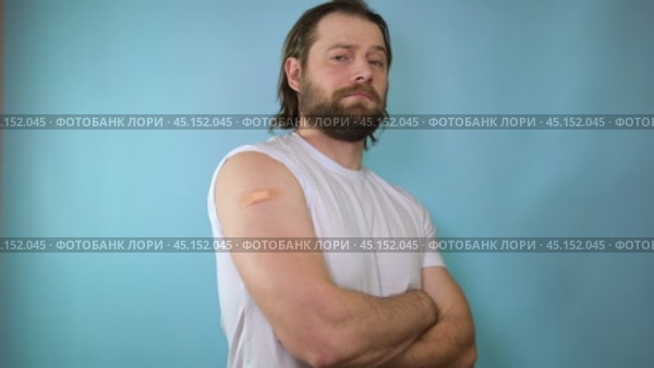 Smiling adult caucasian man show shoulder with band aid after injection. Bearded man in antiviral mask gesturing thumb up during coronavirus vaccination, approving of covid-19 immunization. Стоковое видео, видеограф Марина Демидюк / Фотобанк Лори
