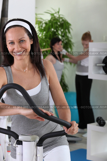 Smiling brown-haired woman on cross trainer. Стоковое фото, агентство Ingram Publishing / Фотобанк Лори