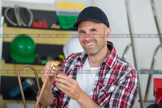 smiling plumber using welding gas torch to solder copper pipes. Стоковое фото, агентство Ingram Publishing / Фотобанк Лори