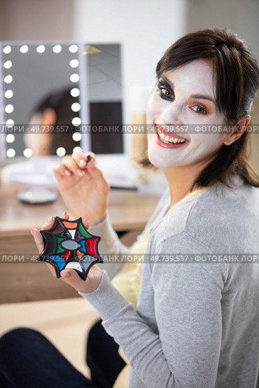 smiling woman applying halloween make-up. Стоковое фото, агентство Ingram Publishing / Фотобанк Лори
