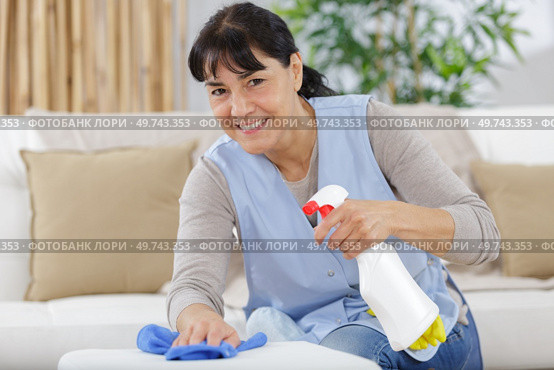 smiling woman spraying cleaning liquid on a table. Стоковое фото, агентство Ingram Publishing / Фотобанк Лори