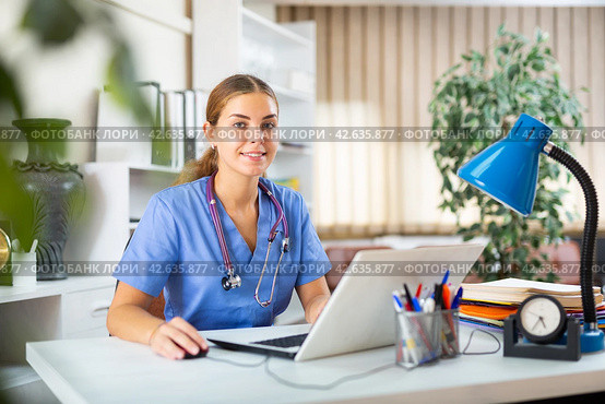 Smiling young woman therapist filling up medical forms on laptop in office. Стоковое фото, фотограф Яков Филимонов / Фотобанк Лори