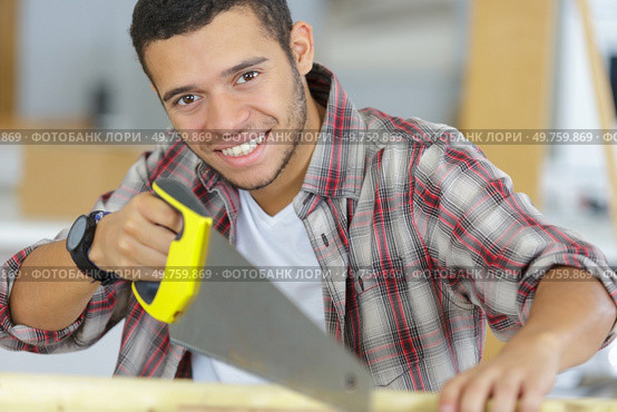 smily young workman using handsaw. Стоковое фото, агентство Ingram Publishing / Фотобанк Лори
