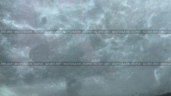 Snow flakes falling on a glass window, snow gliding and melting across glass. Background, Space for text. Стоковое видео, видеограф Сахарова Мария Юрьевна / Фотобанк Лори