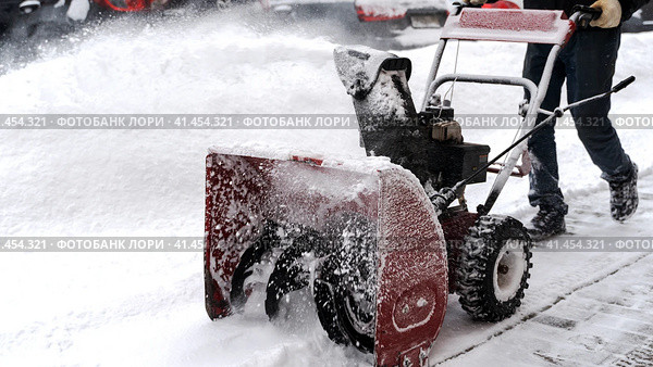 Snowblower removes snow, a man cleans the yard outside. Стоковое фото, фотограф Igor Skripachev / Фотобанк Лори