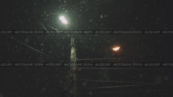 Snowfall on the background of a lantern in winter at night. Стоковое видео, видеограф Георгий Мякишев / Фотобанк Лори