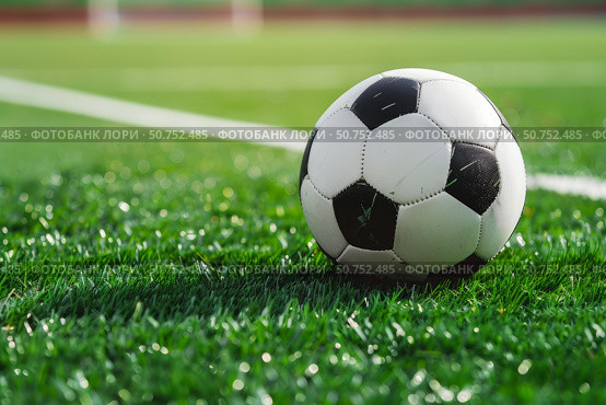 Soccer ball resting on lush green artificial turf field. Стоковое AI-изображение, AI-художник Иван Рябоконь / Фотобанк Лори