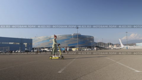 Sochi, Russia - 10 October, 2024: A red-haired beautiful woman rides a Yandex electric scooter in the Olympic Park. Стоковое видео, видеограф Арзюков Вадим Николаевич / Фотобанк Лори