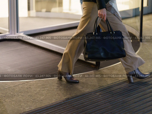 Somebody leaving the building in Moscow city. Woman leaving  modern office building in night. She is going home after long business day. Occupation theme. Low angle view. Стоковое фото, фотограф YuryKara / Фотобанк Лори