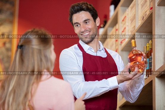 sommelier in wine store giving woman recommendation. Стоковое фото, агентство Ingram Publishing / Фотобанк Лори