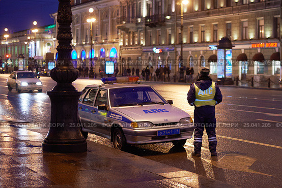 Сотрудник ДПС ГИБДД дежурит на улице города вечером рядом с автомобилем со спецсигналами (2014 год). Редакционное фото, фотограф Иван Козлович / Фотобанк Лори