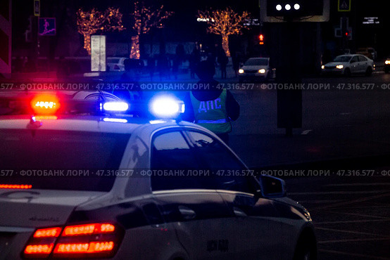 Сотрудники ДПС с автомобилем с включенным проблесковым маячком ведут патрулирование на улице в центре города Москвы, Россия (2017 год). Редакционное фото, фотограф Николай Винокуров / Фотобанк Лори