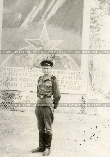 Советский военный на фоне большого плаката, СССР, 1970-е гг. Стоковое фото, фотограф Retro / Фотобанк Лори