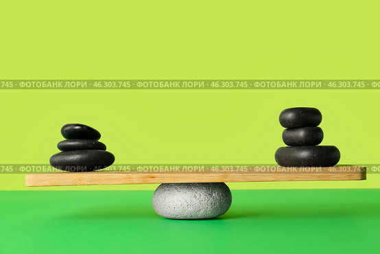 Spa stones on teeterboard against green background. Concept of balance. Стоковое фото, фотограф Pixel_shot / Фотобанк Лори