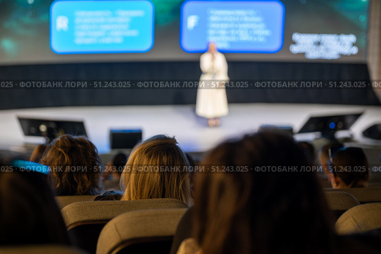 Speaker presenting at conference viewed from audience perspective in modern auditorium. Стоковое фото, фотограф Антон Гвоздиков / Фотобанк Лори