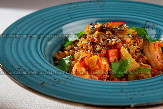 Spicy Korean style kimchi fried rice with shrimp, bell pepper, sesame seeds and fresh cilantro served in a rustic blue ceramic bowl on white background. Стоковое фото, фотограф Aleksandr Gavrilychev / Фотобанк Лори