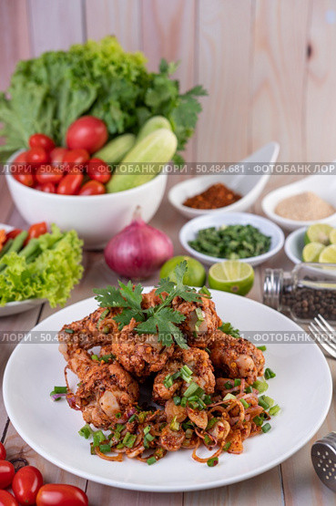 Spicy minced chicken on a white plate complete with cucumber, lettuce and side dishes on wooden table. Стоковое фото, агентство Ingram Publishing / Фотобанк Лори