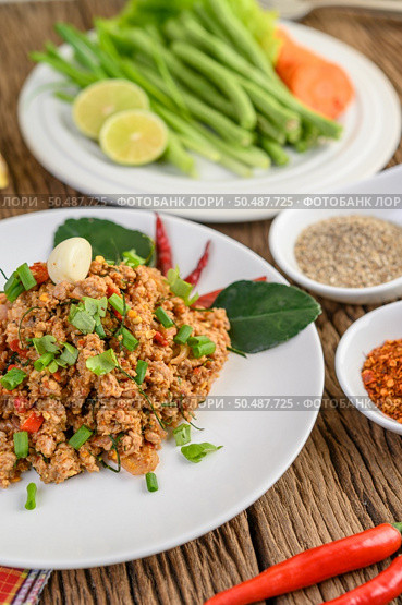 Spicy Minced Pork Salad on a white plate with red onion, lemon grass, garlic, yardlong beans, kaffir lime leaves, and spring onion. Стоковое фото, агентство Ingram Publishing / Фотобанк Лори