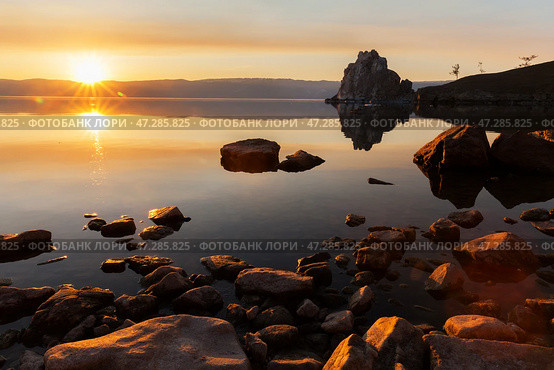Spring landscape of Baikal Lake at sunset in May. View of Shamanka rock or Burkhan cape, Small Sea and stone beach of Olkhon Island at dusk in the light of the setting sun. Beautiful calm landscape. Стоковое фото, фотограф Виктория Катьянова / Фотобанк Лори