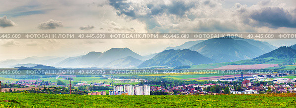 Spring storm in mountains panorama. Overcast dramatic sky over Liptov town in Slovakia. Dandelion meadow. Стоковое фото, агентство Ingram Publishing / Фотобанк Лори