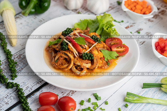 Squid fried with curry paste in white plate, with vegetables and side dishes on a white wooden floor. Selective focus. Стоковое фото, агентство Ingram Publishing / Фотобанк Лори