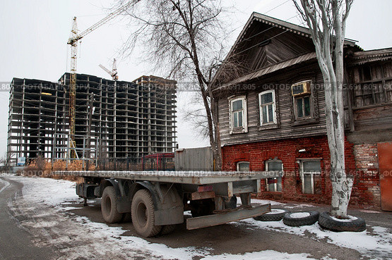 Старый  дом времен Российской империи в исторической части старого города Астрахань ( Южная часть города ). С обеих сторон надвигаются новостройки, и он обречен на снос (2018 год). Стоковое фото, фотограф Павел Просянов / Фотобанк Лори