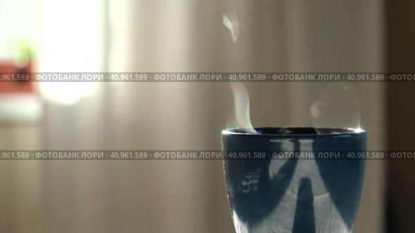 Steaming Cup of Coffee or Tea on Table. White linen Tablecloth. Close-up ceramic blue mug with smoke on old table in dining room interior background. Hot Drink Concept. Cozy Morning. Стоковое видео, видеограф Марина Демидюк / Фотобанк Лори