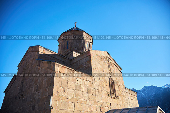 Stepantsminda, Georgia - January 03, 2023: Gergeti Church of the 14th century at the foot of Mount Kazbek. Редакционное фото, фотограф Наталия Кирсанова / Фотобанк Лори