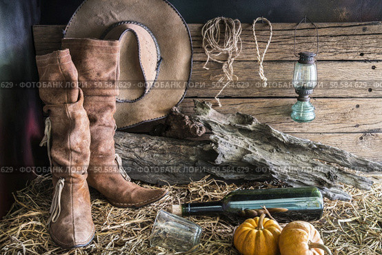 Still life photography with traditional leather boots and american west rodeo brown cowboy hat in vintage ranch barn background. Стоковое фото, агентство Ingram Publishing / Фотобанк Лори
