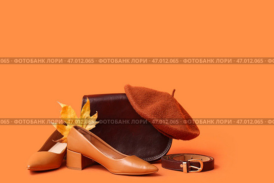 Стильные высокие каблуки с коричневой сумкой, беретом, ремнем и осенним листом на оранжевом фоне. Стоковое фото, фотограф Pixel_shot / Фотобанк Лори