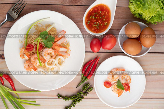 Stir-fried instant noodle with prawn and crab stick along with tomatoes and peppers in a white plate on a wooden floor. Стоковое фото, агентство Ingram Publishing / Фотобанк Лори
