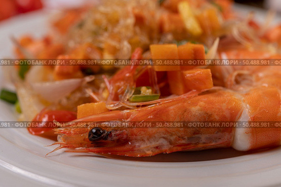 Stir-fried prawns with glass noodles in a white plate placed on a cloth with eggs and garlic. Стоковое фото, агентство Ingram Publishing / Фотобанк Лори