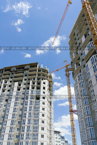 Строящееся высотное здание и подъемный кран на фоне голубого неба. Building crane and building under construction against blue sky. Стоковое фото, фотограф Татьяна Д / Фотобанк Лори