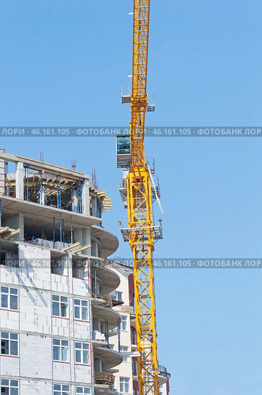 Строящееся высотное здание и подъемный кран на фоне голубого неба. Building crane and building under construction against blue sky. Стоковое фото, фотограф Татьяна Д / Фотобанк Лори
