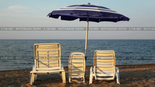 Стулья трех габаритов находятся на берегу моря под зонтиком. Стоковое видео, видеограф Losevsky Pavel / Фотобанк Лори