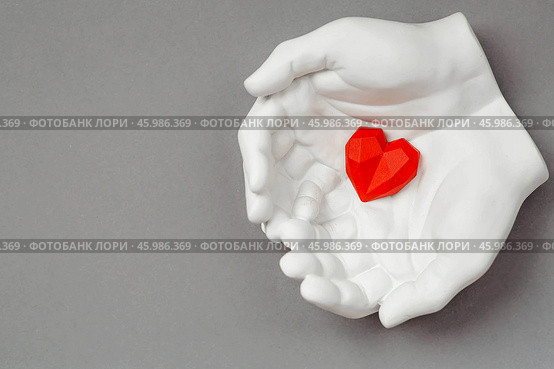 Stylish banner. In his hands, a red heart on a gray background is made of plaster. World Health, Love and Insurance Day. World Heart, Health and Organ Donor Day. Стоковое фото, фотограф Photojuli / Фотобанк Лори
