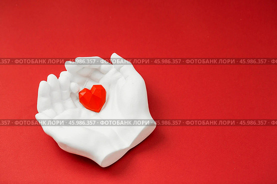 Stylish banner. In his hands, a red heart on a red background is made of plaster. World Health, Love and Insurance Day. World Heart, Health and Organ Donor Day. Стоковое фото, фотограф Photojuli / Фотобанк Лори